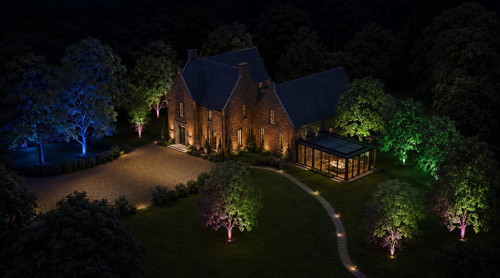 Villa at night with illuminated driveway, pathways and colour-accented trees
